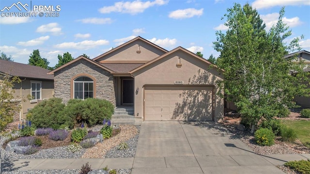 5060 Galloping Goose Way, Colorado Springs, CO 80924 - view of front of house featuring an attached garage, stucco siding, driveway, and stone siding