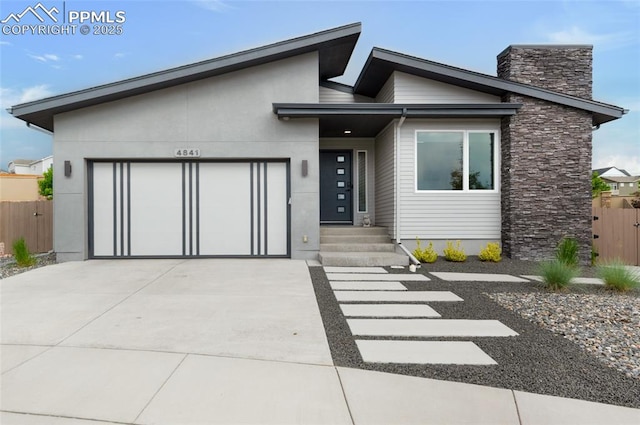 4841 Hanging Lake Cir, Colorado Springs, CO 80924 - modern home with a garage, driveway, stone siding, and a chimney