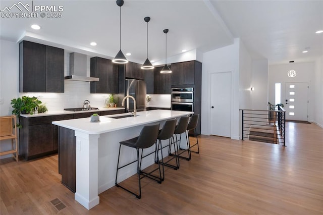 4841 Hanging Lake Cir, Colorado Springs, CO 80924 - kitchen with wall chimney range hood, appliances with stainless steel finishes, backsplash, light wood-type flooring, and recessed lighting