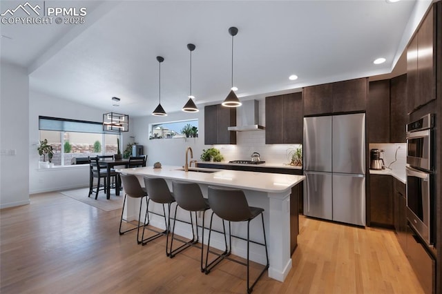 4841 Hanging Lake Cir, Colorado Springs, CO 80924 - kitchen with stainless steel appliances, wall chimney range hood, a kitchen bar, decorative backsplash, and dark brown cabinets