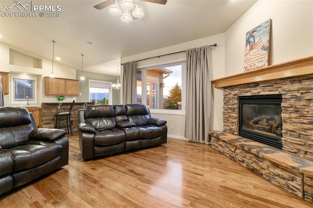 6972 Granite Peak Dr, Colorado Springs, CO 80923 - living room with a stone fireplace, ceiling fan, light wood finished floors, and vaulted ceiling