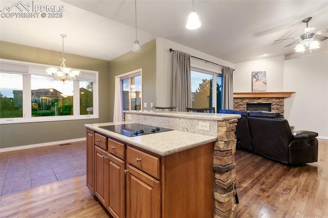 6972 Granite Peak Dr, Colorado Springs, CO 80923 - kitchen with black electric stovetop, brown cabinetry, a fireplace, open floor plan, and light countertops