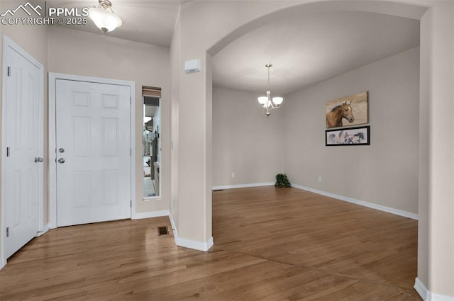 7665 Manston Dr, Colorado Springs, CO 80920 - foyer with arched walkways, a chandelier, and wood finished floors