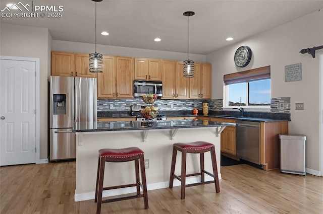 7665 Manston Dr, Colorado Springs, CO 80920 - kitchen with appliances with stainless steel finishes, a center island, a breakfast bar area, backsplash, and light wood finished floors