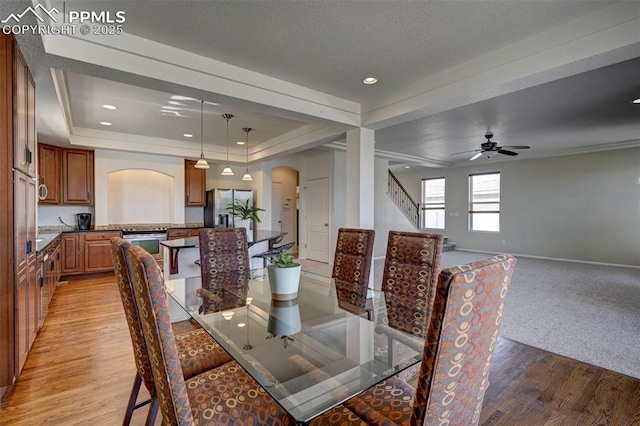 9444 Castle Oaks Dr, Fountain, CO 80817 - dining space featuring arched walkways, light wood-style floors, stairs, a raised ceiling, and a ceiling fan