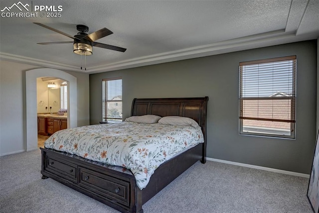 9444 Castle Oaks Dr, Fountain, CO 80817 - bedroom featuring carpet flooring, arched walkways, a textured ceiling, ensuite bathroom, and a raised ceiling
