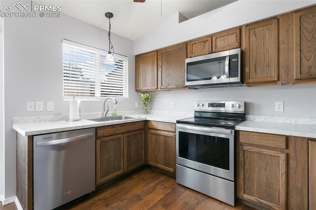 1360 Piros Dr, Colorado Springs, CO 80922 - kitchen featuring appliances with stainless steel finishes, brown cabinetry, dark wood finished floors, and light countertops