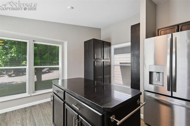 4680 Pika Pt, Colorado Springs, CO 80922 - kitchen with stainless steel fridge, dark countertops, light wood-style flooring, and a center island