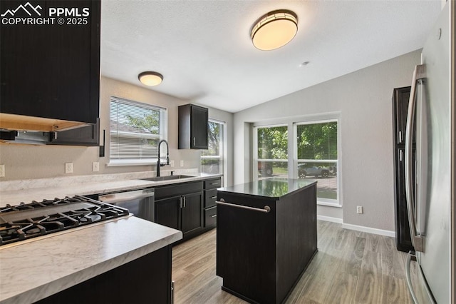 4680 Pika Pt, Colorado Springs, CO 80922 - kitchen with freestanding refrigerator, dishwashing machine, dark cabinetry, a kitchen island, and light wood-type flooring