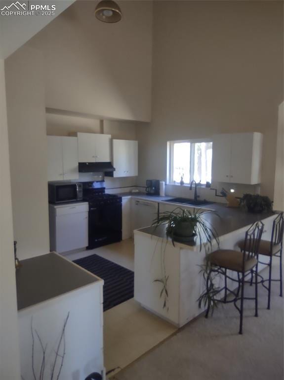 423 Ridge Rd, Divide, CO 80814 - kitchen featuring black range with gas stovetop, high vaulted ceiling, stainless steel microwave, white cabinets, and under cabinet range hood