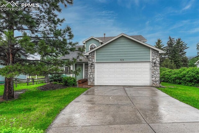 123 Wheat Ridge St, Palmer Lake, CO 80133 - view of front of house featuring stone siding, driveway, a front yard, and an attached garage