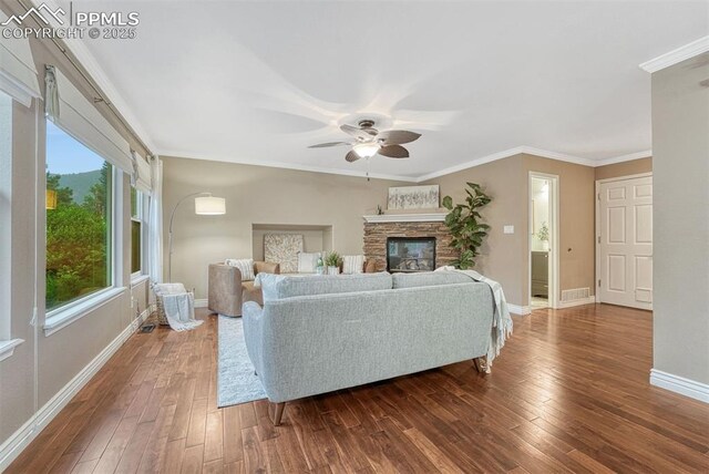 123 Wheat Ridge St, Palmer Lake, CO 80133 - living room with ceiling fan, dark wood-style flooring, crown molding, and a stone fireplace