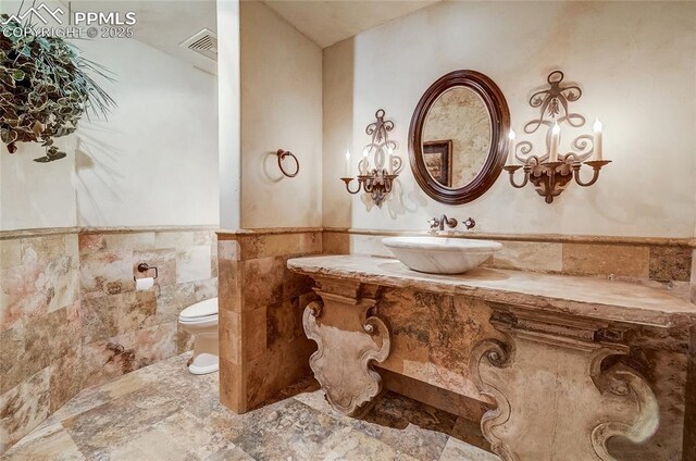 910 Grey Mountain Pt, Colorado Springs, CO 80906 - bathroom with tile walls, a wainscoted wall, and vanity