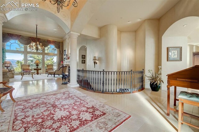 910 Grey Mountain Pt, Colorado Springs, CO 80906 - hall featuring a chandelier, tile patterned floors, arched walkways, ornate columns, and ornamental molding
