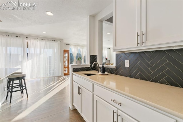 13437 Park Meadows Dr, Peyton, CO 80831 - kitchen featuring decorative backsplash, white cabinets, light countertops, wood finished floors, and recessed lighting