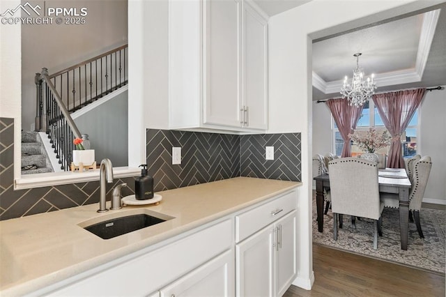 13437 Park Meadows Dr, Peyton, CO 80831 - kitchen featuring white cabinets, wood finished floors, ornamental molding, a chandelier, and light countertops