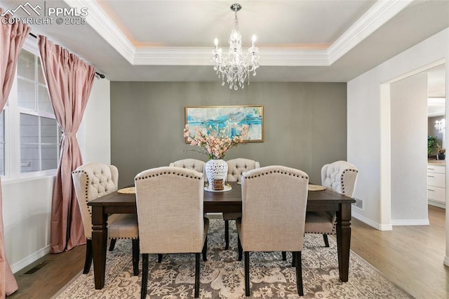 13437 Park Meadows Dr, Peyton, CO 80831 - dining space featuring a chandelier, wood finished floors, a tray ceiling, and crown molding
