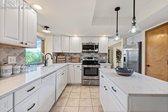 2505 Wimbleton Ct, Colorado Springs, CO 80920 - kitchen featuring appliances with stainless steel finishes, tasteful backsplash, white cabinetry, light tile patterned floors, and a center island