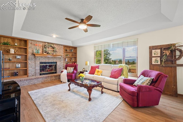 2505 Wimbleton Ct, Colorado Springs, CO 80920 - living area featuring a textured ceiling, a ceiling fan, a raised ceiling, wood finished floors, and a brick fireplace