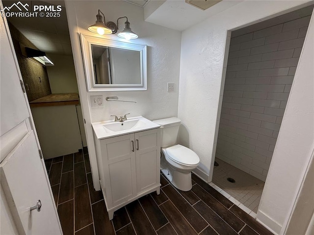 251 Fay Dr, Colorado Springs, CO 80911 - full bathroom with vanity, wood tiled floors, a textured wall, and a tile shower