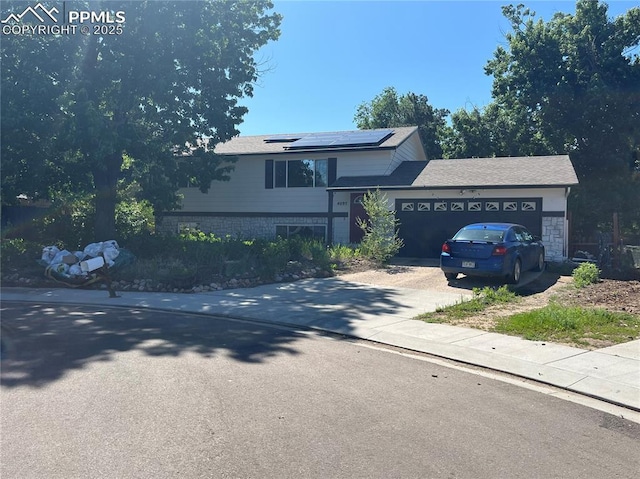 4095 Candea Ct, Colorado Springs, CO 80916 - tri-level home featuring solar panels, an attached garage, concrete driveway, and a shingled roof