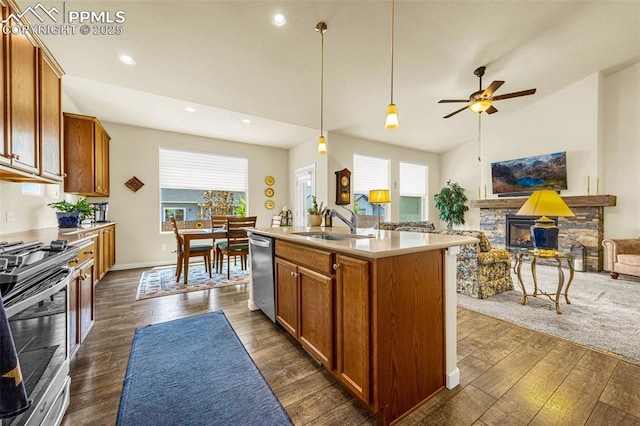 2997 Bright Moon Dr, Colorado Springs, CO 80908 - kitchen featuring stainless steel appliances, open floor plan, a stone fireplace, light countertops, and brown cabinets