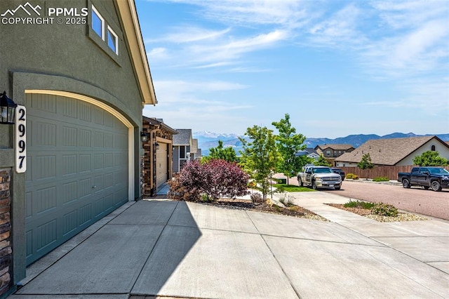 2997 Bright Moon Dr, Colorado Springs, CO 80908 - view of side of home featuring concrete driveway, a mountain view, an attached garage, a residential view, and stucco siding