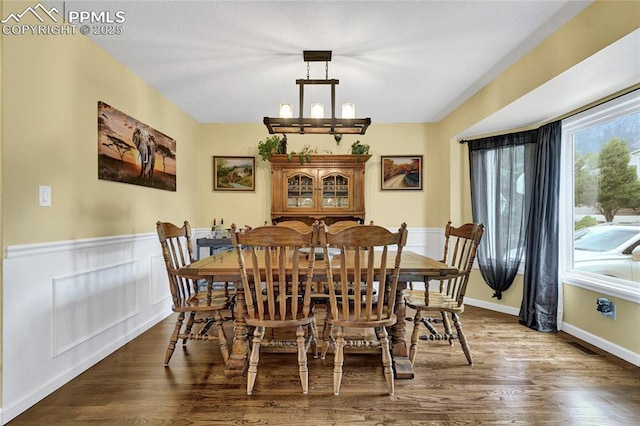 35 Lowick Dr, Colorado Springs, CO 80906 - dining area with dark wood-style floors, a chandelier, and a wainscoted wall