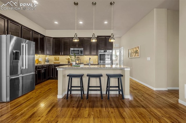 4187 Notch Trl, Colorado Springs, CO 80924 - kitchen featuring stainless steel appliances, tasteful backsplash, dark wood finished floors, a kitchen breakfast bar, and light stone countertops