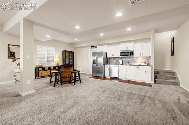 4187 Notch Trl, Colorado Springs, CO 80924 - kitchen featuring appliances with stainless steel finishes, light carpet, white cabinetry, decorative backsplash, and recessed lighting