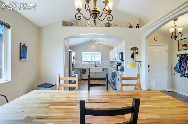 7544 Lake Ave, Fountain, CO 80817 - dining space featuring a chandelier, vaulted ceiling, arched walkways, and wood finished floors