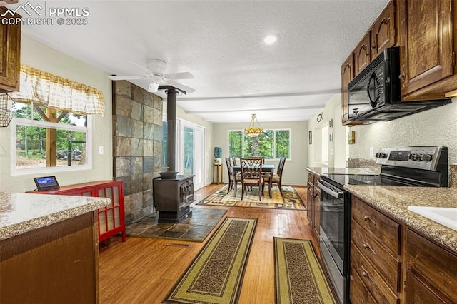 269 Evergreen Rd, Woodland Park, CO 80863 - kitchen featuring stainless steel electric range oven, a wood stove, black microwave, a textured ceiling, and wood finished floors