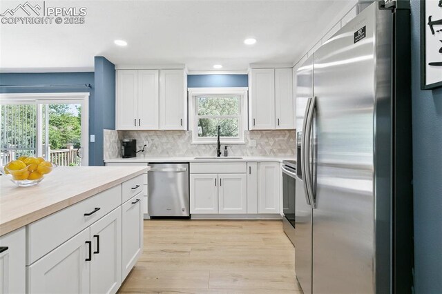 4603 Bella Dr, Colorado Springs, CO 80918 - kitchen featuring appliances with stainless steel finishes, white cabinets, tasteful backsplash, light wood-style flooring, and recessed lighting