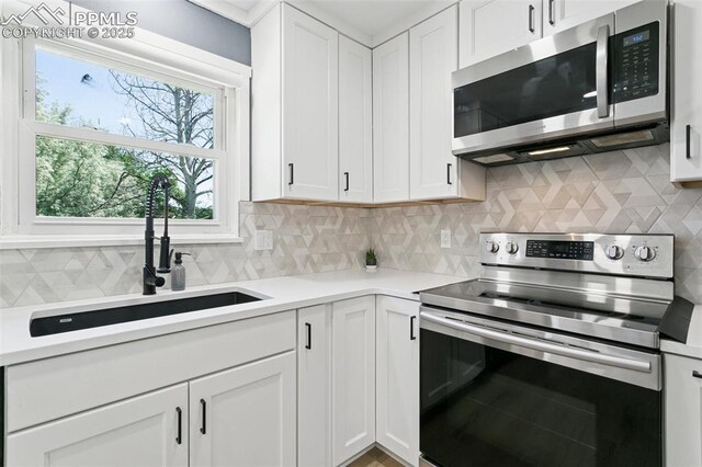 4603 Bella Dr, Colorado Springs, CO 80918 - kitchen featuring stainless steel appliances, decorative backsplash, white cabinets, and light countertops