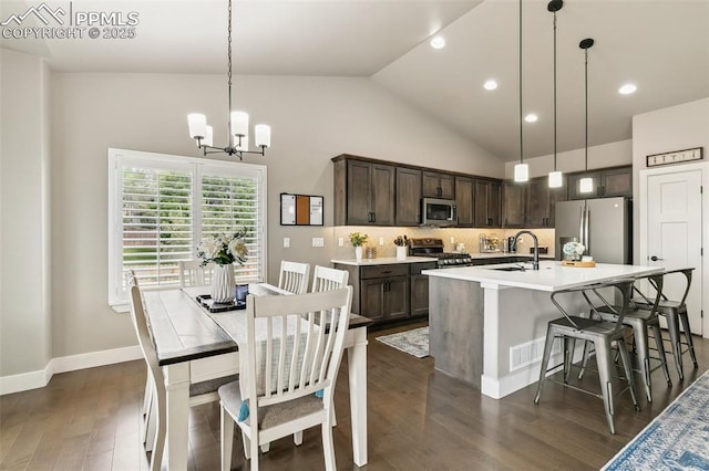6792 David Anthony Ct, Colorado Springs, CO 80922 - kitchen with appliances with stainless steel finishes, dark brown cabinets, a chandelier, a kitchen island with sink, and dark wood-style floors