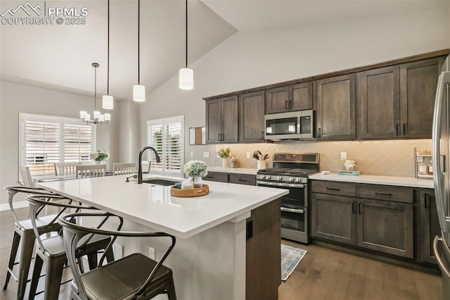 6792 David Anthony Ct, Colorado Springs, CO 80922 - kitchen featuring stainless steel appliances, a breakfast bar area, dark brown cabinetry, backsplash, and high vaulted ceiling