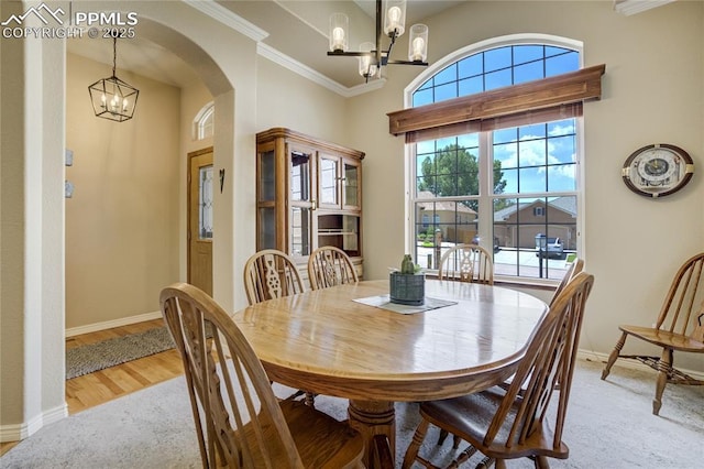 5763 Show Down Ln, Colorado Springs, CO 80923 - dining area featuring a chandelier, a towering ceiling, arched walkways, light wood-type flooring, and crown molding