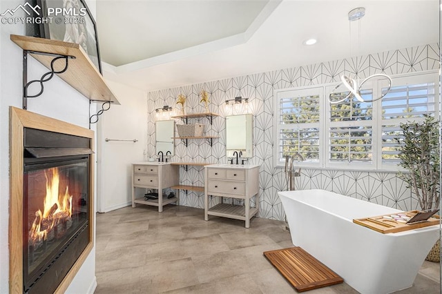 17870 New London Rd, Monument, CO 80132 - full bath with double vanity, a freestanding tub, a glass covered fireplace, healthy amount of natural light, and recessed lighting