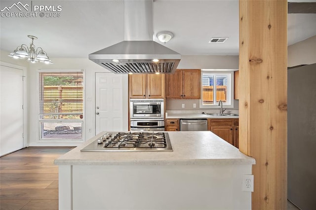 4703 N Weber St, Colorado Springs, CO 80907 - kitchen with island range hood, appliances with stainless steel finishes, brown cabinets, wood finished floors, and plenty of natural light