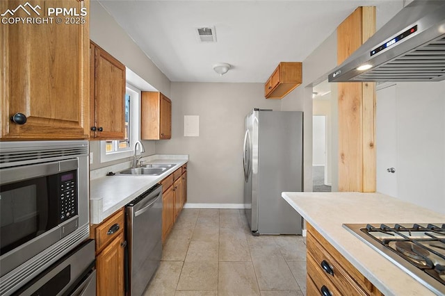 4703 N Weber St, Colorado Springs, CO 80907 - kitchen with wall chimney range hood, appliances with stainless steel finishes, brown cabinetry, and light countertops