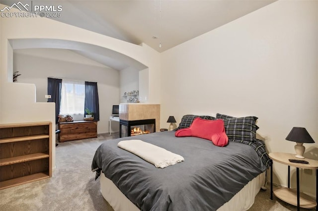 968 Samuel Pt, Colorado Springs, CO 80906 - bedroom featuring vaulted ceiling, carpet, arched walkways, and a tile fireplace