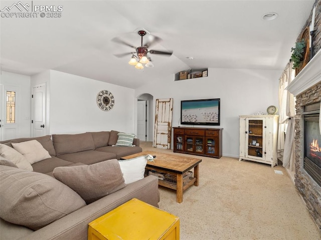 1205 N Picketwire Ln, Pueblo West, CO 81007 - carpeted living room with a fireplace, arched walkways, a ceiling fan, and vaulted ceiling
