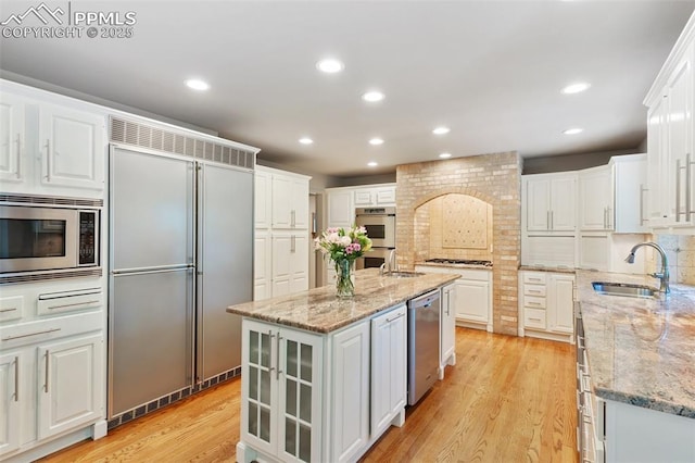 155 Grayson Ct, Colorado Springs, CO 80906 - kitchen with built in appliances, light wood-type flooring, white cabinets, tasteful backsplash, and recessed lighting