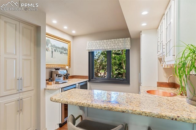 155 Grayson Ct, Colorado Springs, CO 80906 - kitchen with a breakfast bar, recessed lighting, wine cooler, light stone countertops, and a peninsula