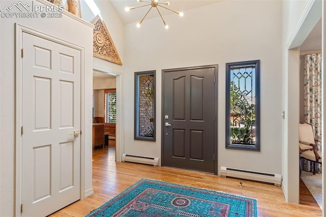 155 Grayson Ct, Colorado Springs, CO 80906 - foyer entrance with a baseboard heating unit, light wood finished floors, a chandelier, and a towering ceiling
