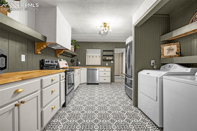 601 N 15th St, Canon City, CO 81212 - kitchen featuring appliances with stainless steel finishes, washing machine and clothes dryer, open shelves, white cabinetry, and wood walls