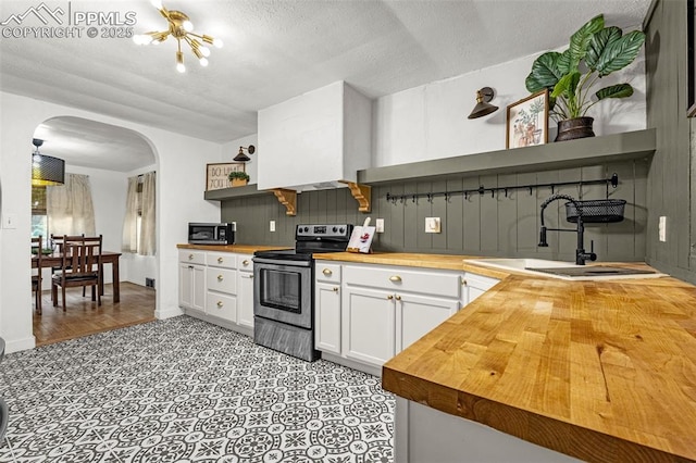 601 N 15th St, Canon City, CO 81212 - kitchen featuring open shelves, wooden counters, stainless steel appliances, arched walkways, and white cabinets