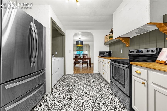 601 N 15th St, Canon City, CO 81212 - kitchen featuring stainless steel appliances, washing machine and dryer, arched walkways, wood counters, and white cabinetry