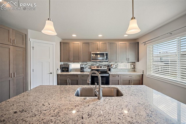 4928 Wolf Moon Dr, Colorado Springs, CO 80911 - kitchen featuring stainless steel appliances, hanging light fixtures, tasteful backsplash, light stone counters, and recessed lighting