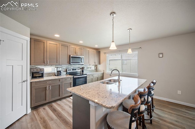 4928 Wolf Moon Dr, Colorado Springs, CO 80911 - kitchen with stainless steel appliances, light wood-style floors, recessed lighting, a breakfast bar area, and tasteful backsplash